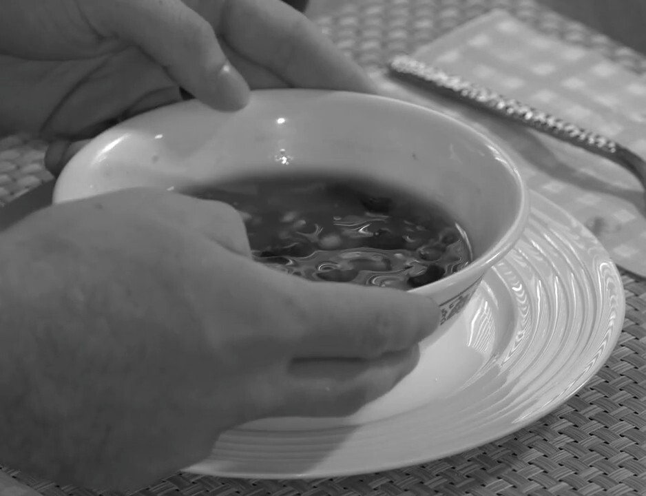 Production still from Pass The Salt — hands tilting a bowl of soup at a dinner table